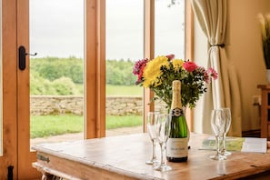 Une table en bois sur laquelle se trouvent une bouteille de champagne Delacourt, deux verres et un bouquet de fleurs.