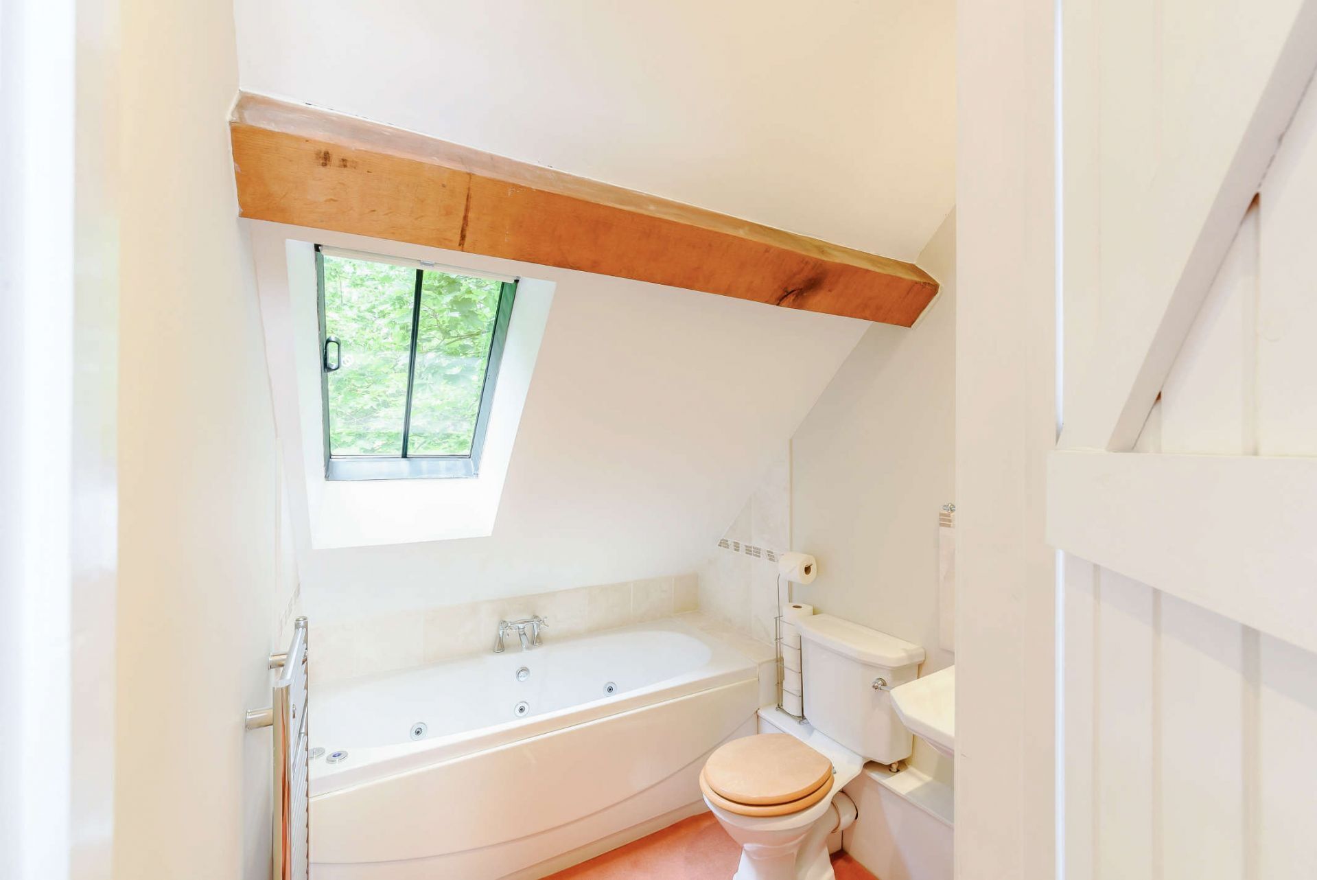 A bathroom with a bathtub, toilet, and a window.