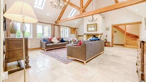 A spacious living room with high ceilings, exposed wooden beams, a chandelier, and a fireplace. - Dog friendly holiday cottage in the Cotswolds with a hot tub - Owls Roost (Cold Aston, near Bourton-on-the-Water)