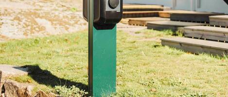 A green utility box with a control panel labeled "Clever" in front of a building with a staircase and a metal railing.