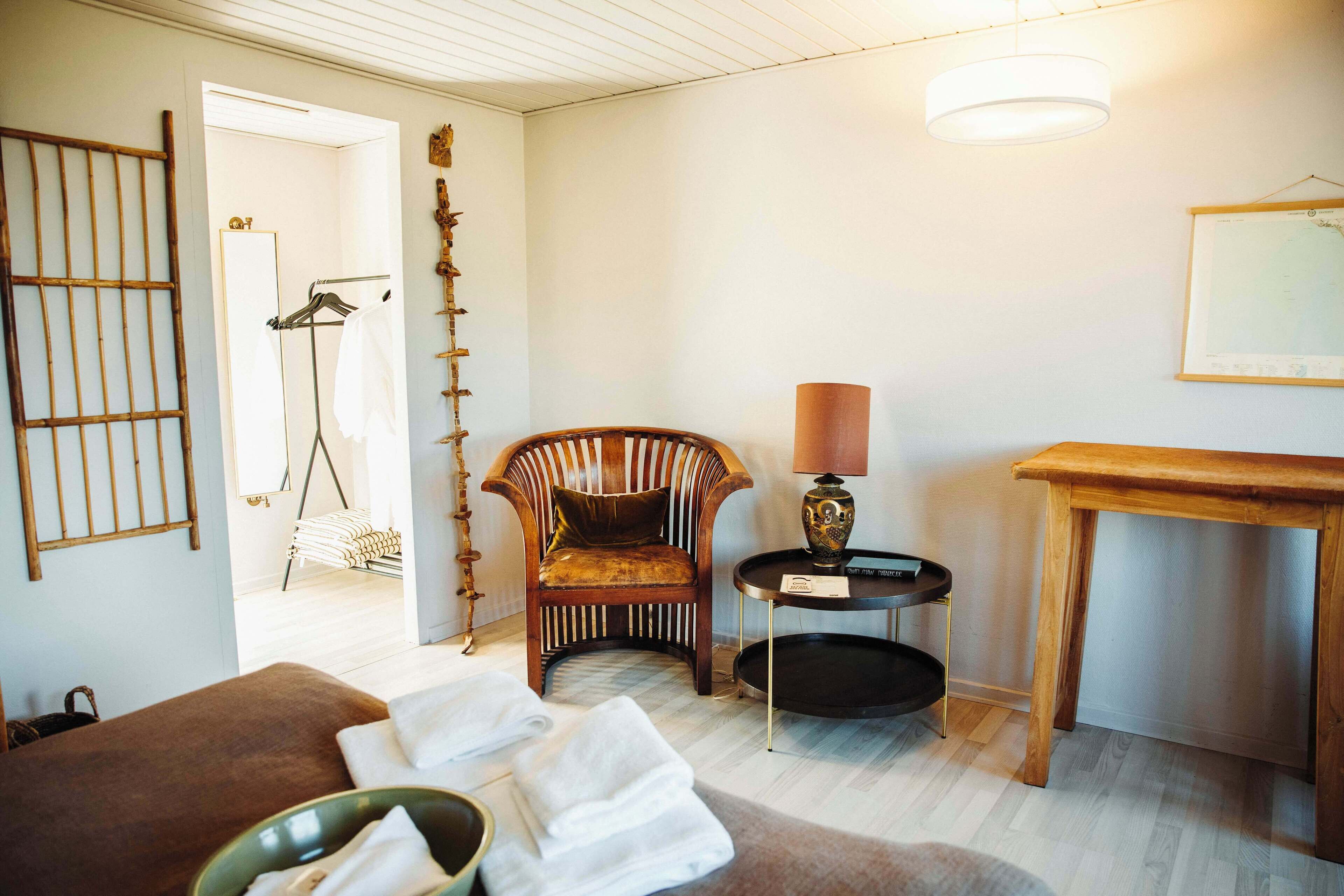 Ett rum med en säng, en stol, ett bord och en lampa.