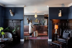 A hotel lobby with a reception desk, a chandelier, and antlered wall decorations. - The Falcon Hotel (Allinge)