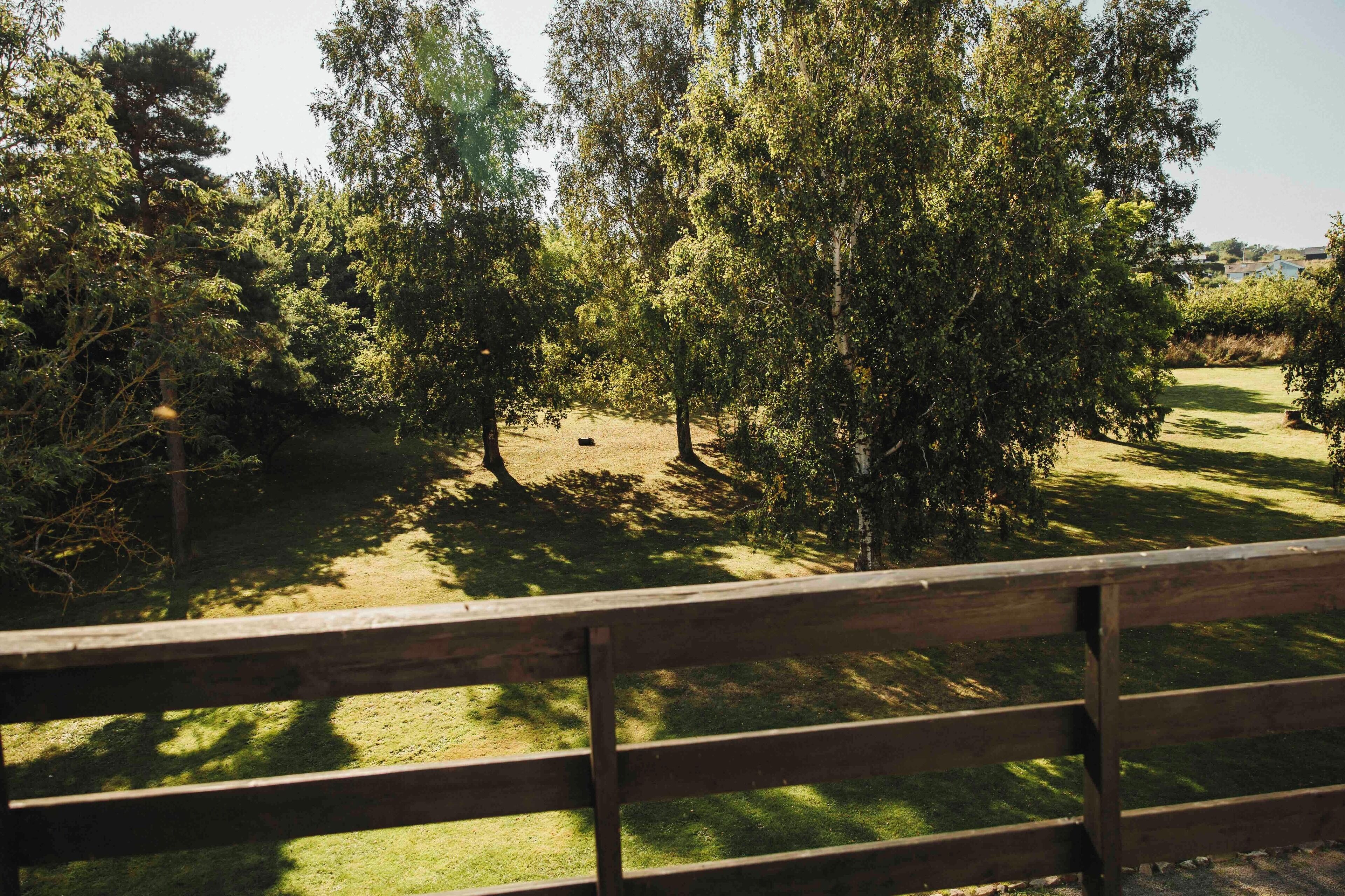 A wooden fence with a grassy area and trees in the background.