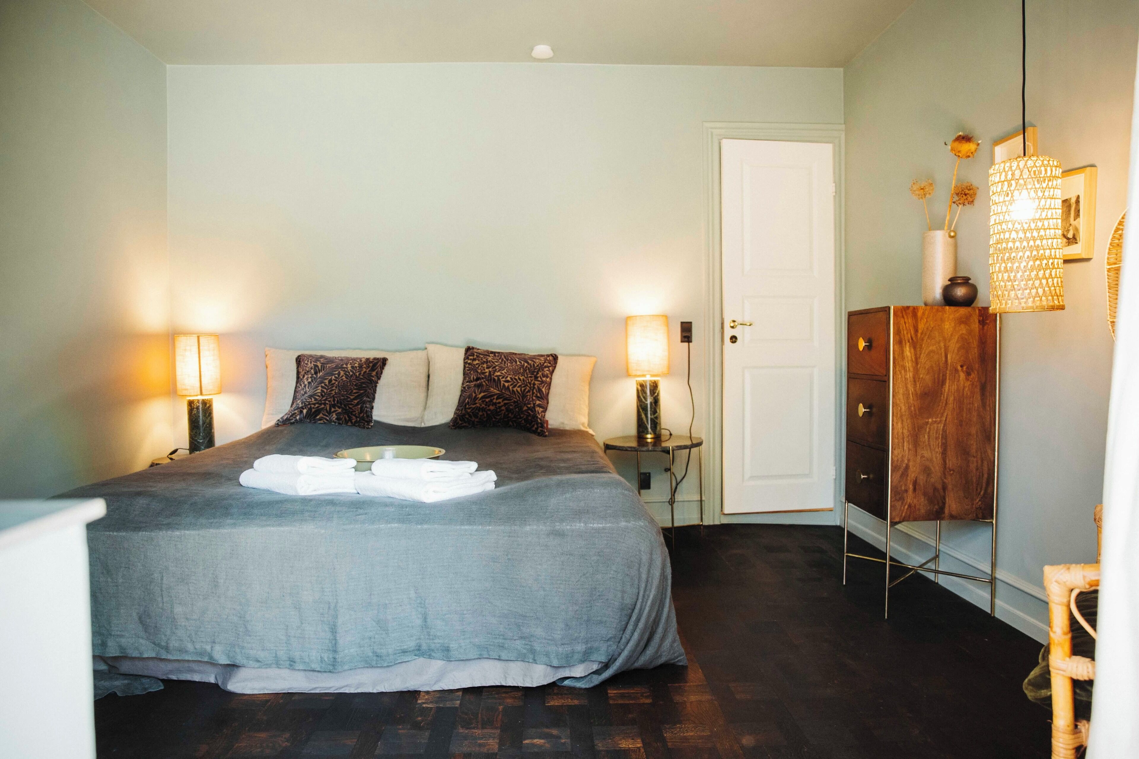 A neatly made bed with pillows, bedside lamps, and a wooden cabinet.