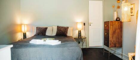 A neatly made bed with pillows, bedside lamps, and a wooden cabinet.