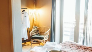 Une chambre d’hôtel avec un lit, une chaise, un porte-vêtements et un bol posé sur le lit.