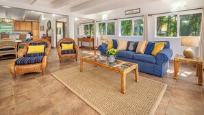 A spacious living area with wicker furniture, a blue sofa, and a glass coffee table. - Private Hanalei house, close to the beach and town! TVNC 1298 (Hanalei)