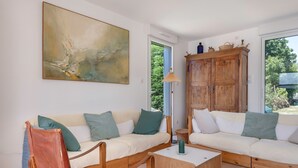 A living room with a sofa set, a wooden cabinet, and a painting on the wall.