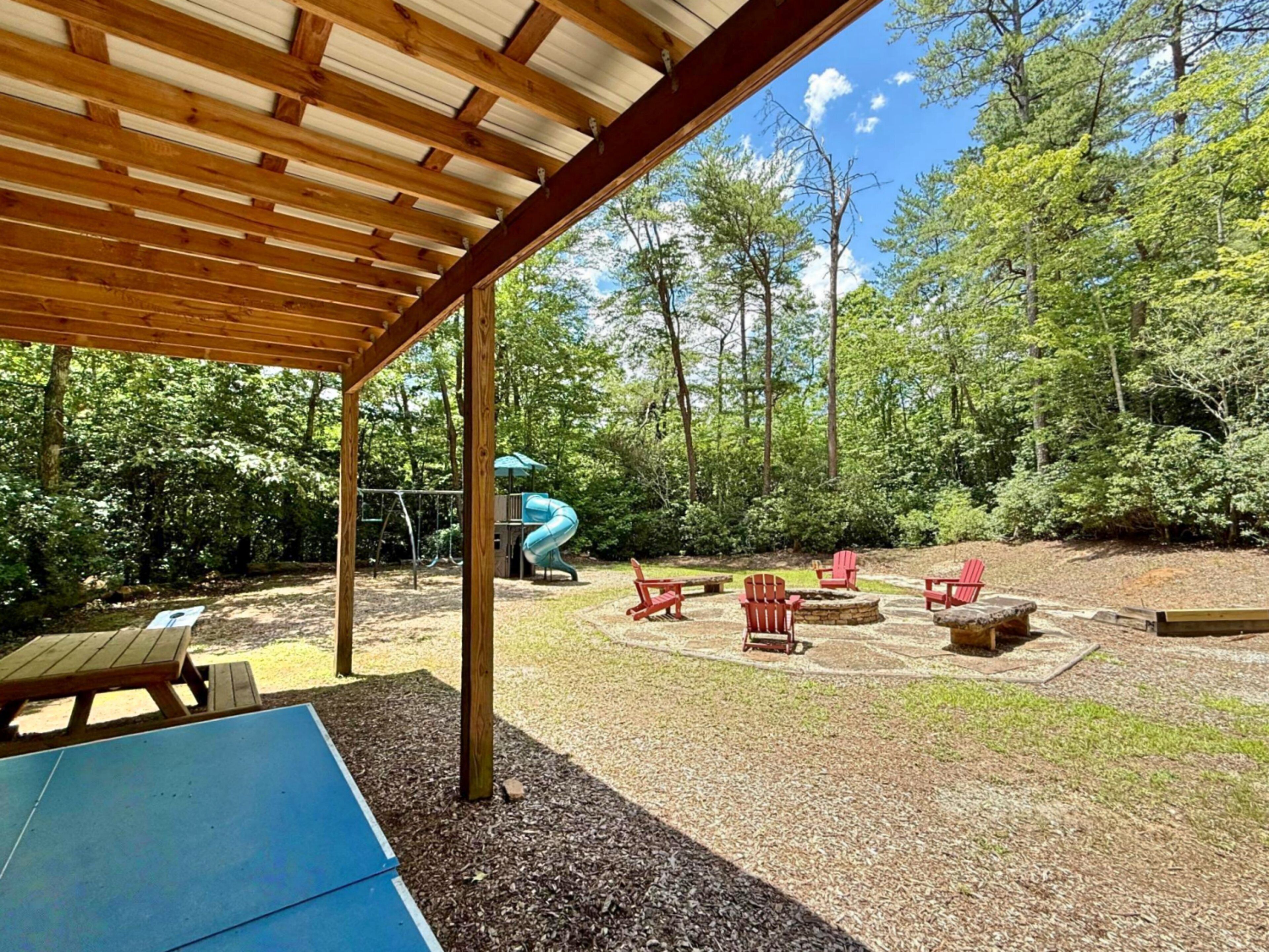 An outdoor patio with a wooden pergola, a children's play area with a slide, and outdoor seating.
