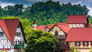 Un bâtiment traditionnel à colombages, avec un toit rouge, entouré d’arbres verdoyants.