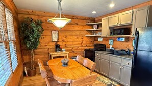 Un intérieur en bois comprenant une table à manger, des chaises, un réfrigérateur, une cuisinière et un four à micro-ondes.