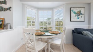 Enjoy a peaceful retreat with a bay window view of lush greenery, a comfortable sofa, and a stylish dining area.