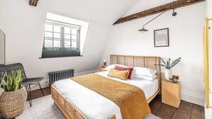 Una camera da letto con un letto, una finestra, un termosifone, un comodino e una pianta in vaso.
