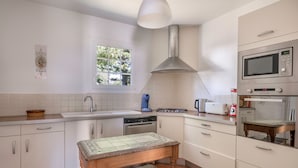 A modern kitchen with white cabinetry, a stainless steel range hood, a microwave, and a built-in oven. - Seafront house - 10 people - Garden (Saint-Gildas-de-Rhuys)