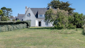A large, single-story house with a sloped roof, a front door, and a visible chimney. - Seafront house - 10 people - Garden (Saint-Gildas-de-Rhuys)