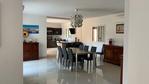 A modern kitchen with dark cabinets, a central island, and a dining area with a large table and chairs. - Family home in Marseille (Marseille)