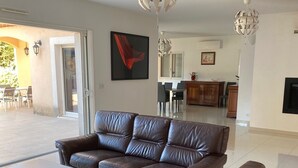 A modern living room with a brown leather sofa, a white coffee table, and a unique spherical chandelier. - Family home in Marseille (Marseille)