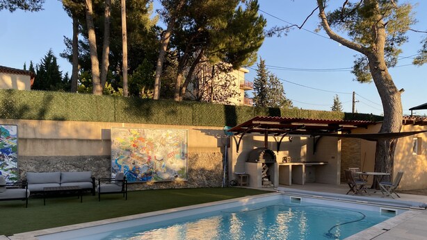 A swimming pool with a pergola and outdoor seating area, surrounded by a landscaped garden and a large mural. - Family home in Marseille (Marseille)