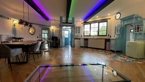 A spacious kitchen with modern appliances, a dining area with a wooden table and chairs, and a colorful patterned rug. - Residenz im "alten Wasserturm" (Wuppertal)