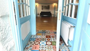 A hallway with a colorful tiled floor leading to a room with a couch and a painting on the wall. - Residenz im "alten Wasserturm" (Wuppertal)