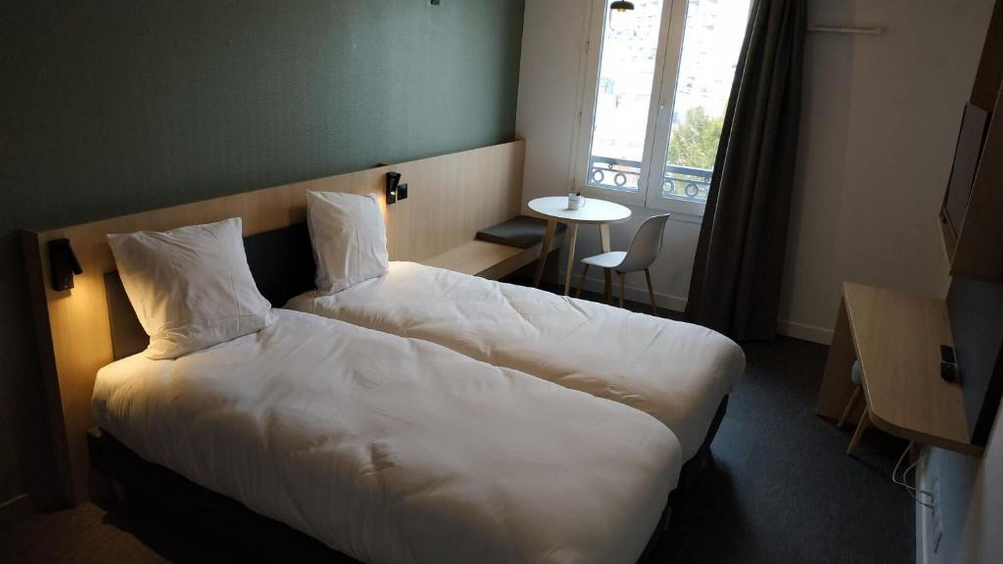 Une chambre d’hôtel avec un lit double, une petite table et une chaise.