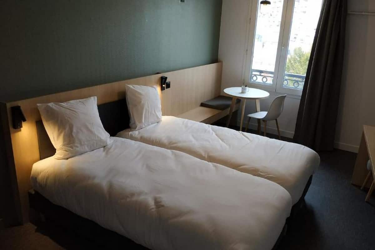 Une chambre d’hôtel avec un lit double, une petite table et une chaise.