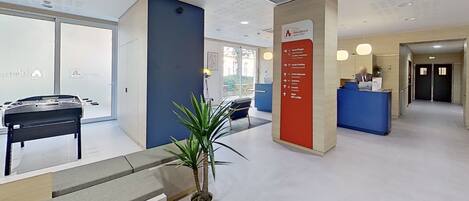 A reception area with a blue counter, a plant, and a signpost with directions.