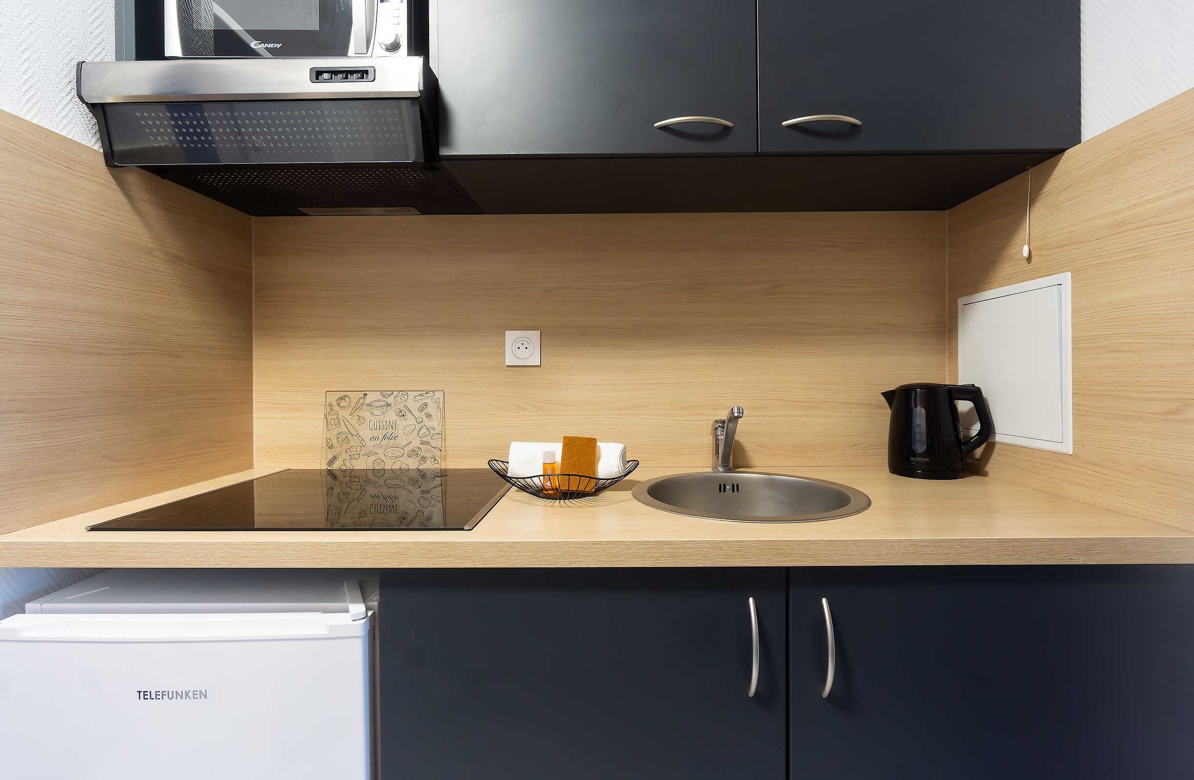 A modern kitchen with a built-in stove, sink, and a kettle.
