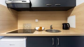 A modern kitchen with a built-in stove, sink, and a kettle.