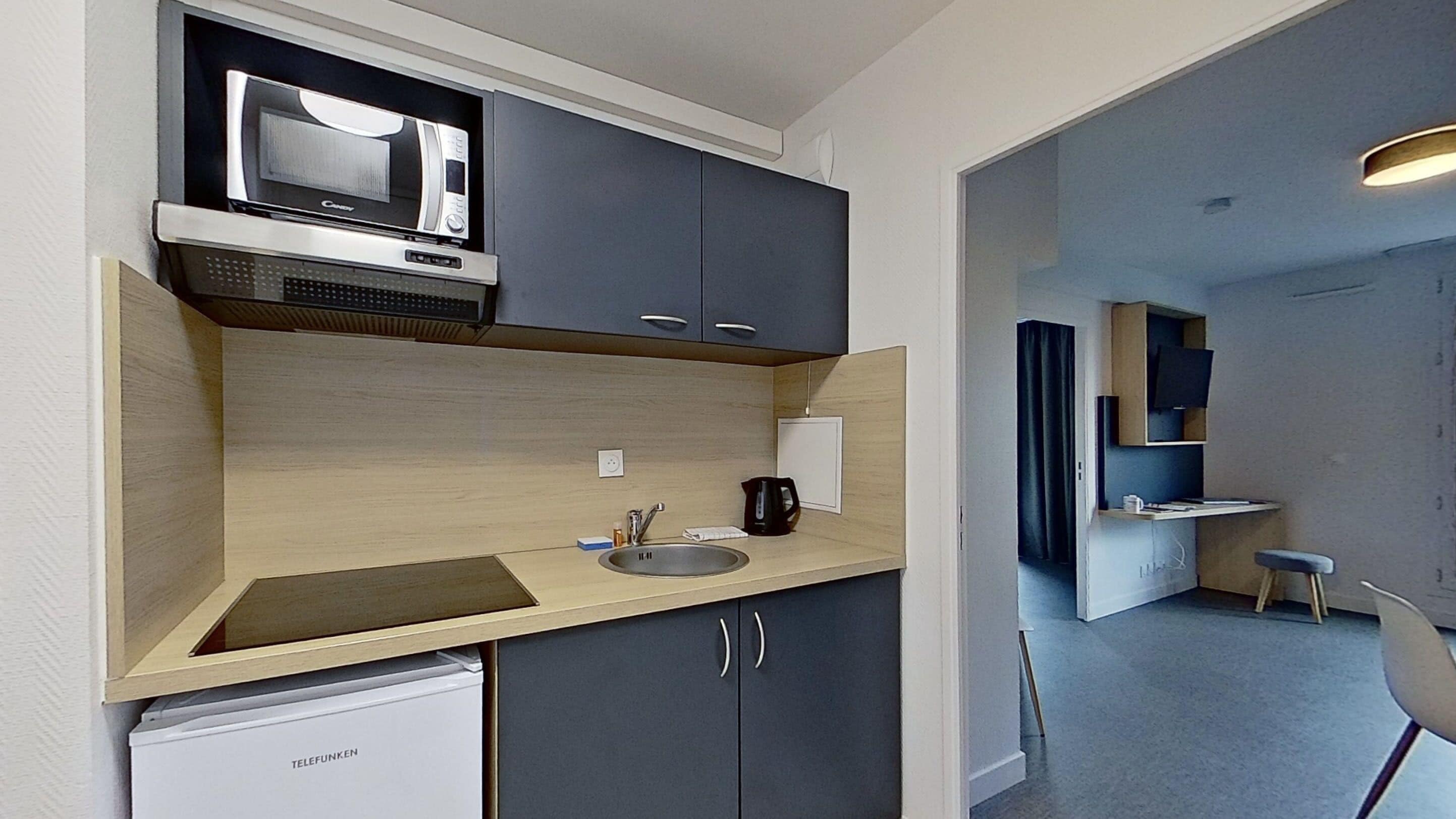 A compact kitchen with a microwave, sink, and a small refrigerator.