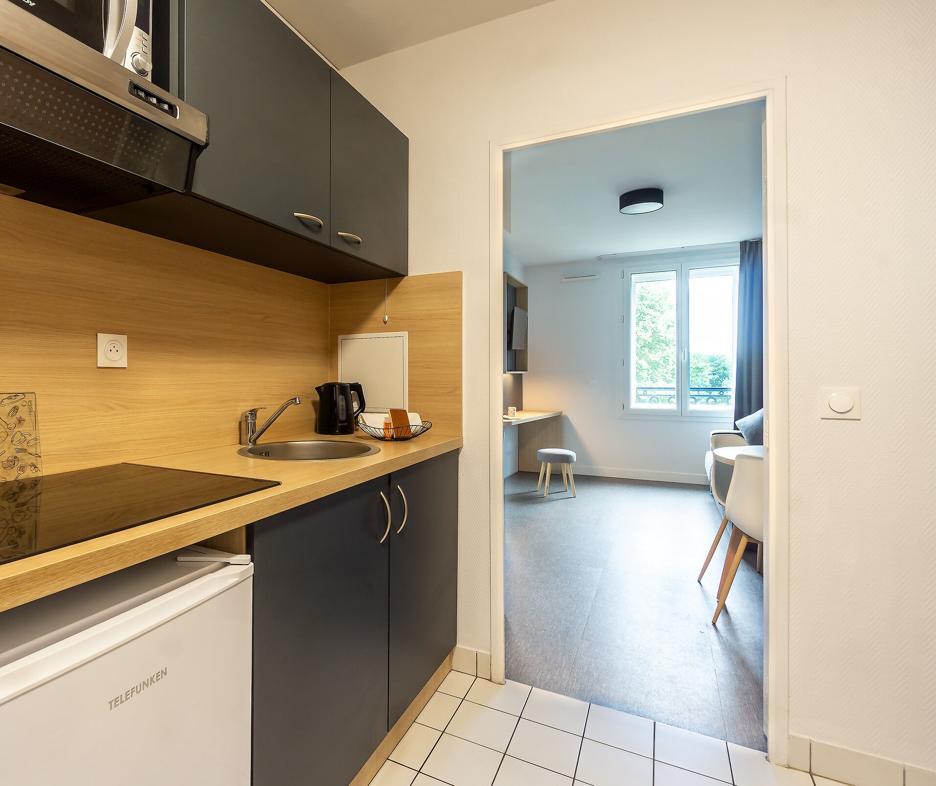 Une cuisine moderne avec des meubles de couleur sombre, un plan de travail en bois et un lave-vaisselle encastré.