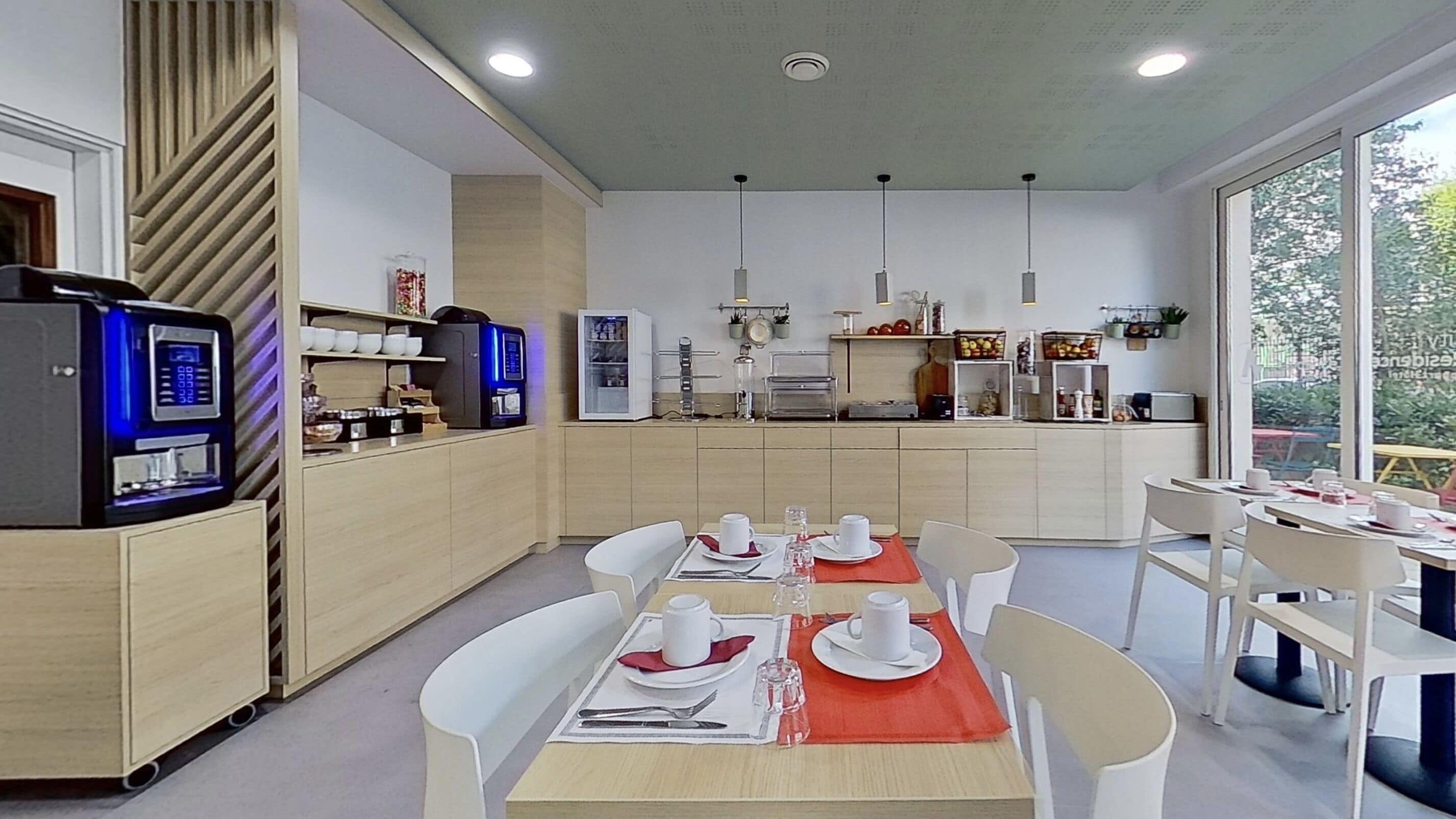 Eine moderne Küche mit Essbereich, ausgestattet mit einer Kaffeemaschine, einem Kühlschrank und einer Mikrowelle.