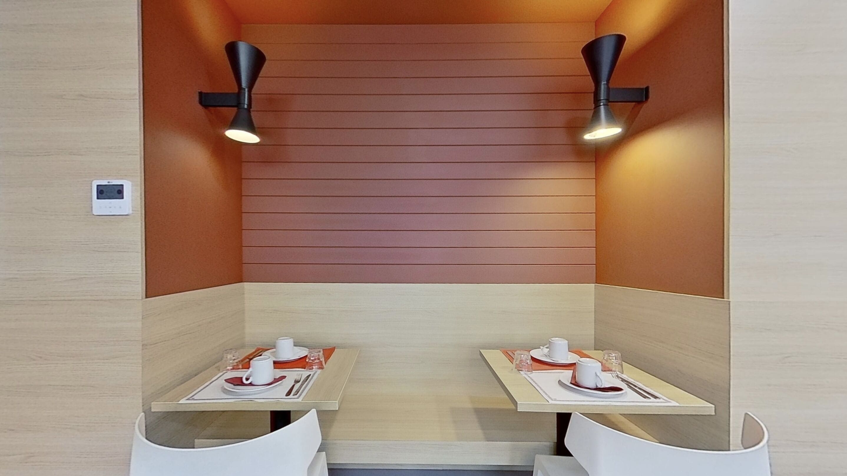 A modern, well-lit room with two tables, each set with a cup, saucer, and cutlery.