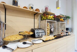 Un bufé de desayuno con diferentes alimentos, un tostador y salsas en una encimera de madera.