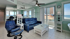 Un salon moderne avec un canapé en cuir bleu, une table basse blanche et un ventilateur de plafond.