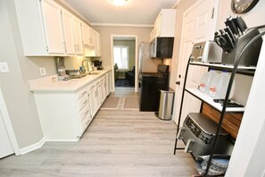 A compact kitchen with white cabinets, a stainless steel range, and a coffee maker.