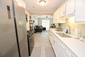 A modern kitchen with white cabinetry, a stainless steel refrigerator, and a built-in oven.