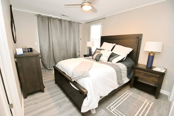 A bedroom with a bed, bedside tables, a nightstand, a desk, a chair, a window with curtains, and a ceiling fan. - 3 blocks from Nd, 3 bedroom 2 bath home(1815) (South Bend)