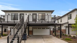 Ein zweistöckiges Haus mit überdachter Veranda, einer Treppe und einer Garage.