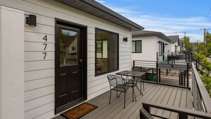 Ein Wohngebäude mit schwarzem Eingangstür, einem Balkon mit Tisch und Stühlen sowie der Hausnummer 47.