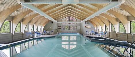 Una piscina interior con un cartel que dice 'NO DIVING', vigas de madera y ventanas amplias.