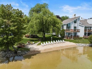 A two-story building with a balcony, surrounded by trees and a small pond. - *NEW* Lakeside Club - 10 Minutes to Harbor Springs and Petoskey! (Petoskey)