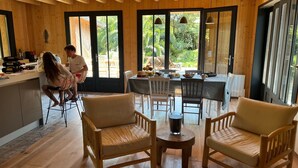 Un intérieur en bois comprenant un coin repas, deux fauteuils confortables et une table avec un plateau en verre.
