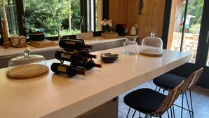 Un comptoir de cuisine avec des bouteilles de vin, une machine à café et une vue sur l’extérieur.