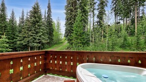 Ein Whirlpool auf einer Holzterrasse mit Blick auf den Wald.