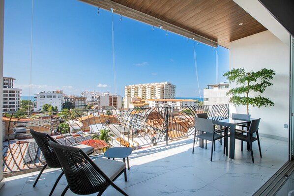 Un balcon offrant une vue sur le paysage urbain, avec des bâtiments et un arbre.