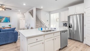 Una cocina moderna con armarios blancos, electrodomésticos de acero inoxidable y una isla central.