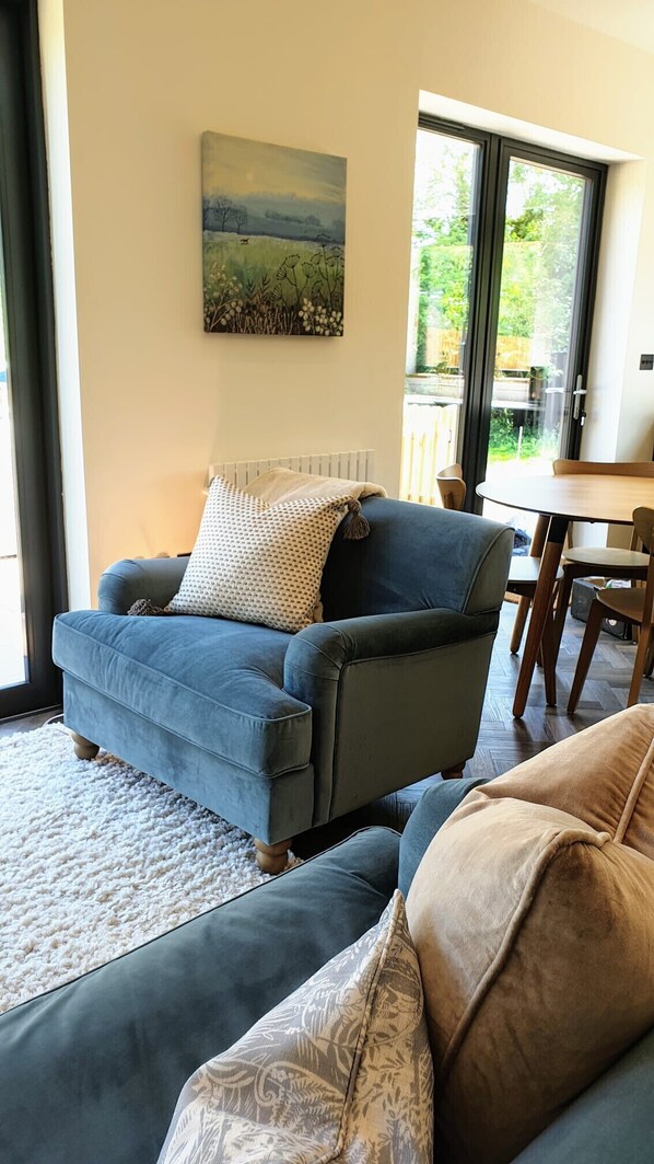 A living room with a blue sofa, a patterned throw pillow, and a painting on the wall.