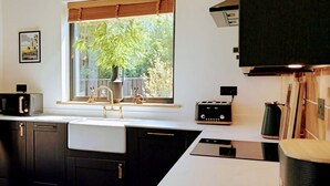Ett modernt kök med mörka skåp, en vit bänkskiva, ett fönster med utsikt över grönområden och en gammal radio.