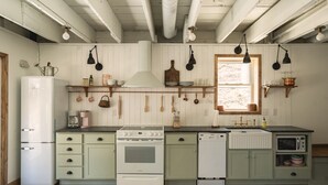 Een keuken met witte kasten, een fornuis, een vaatwasser en een raam.